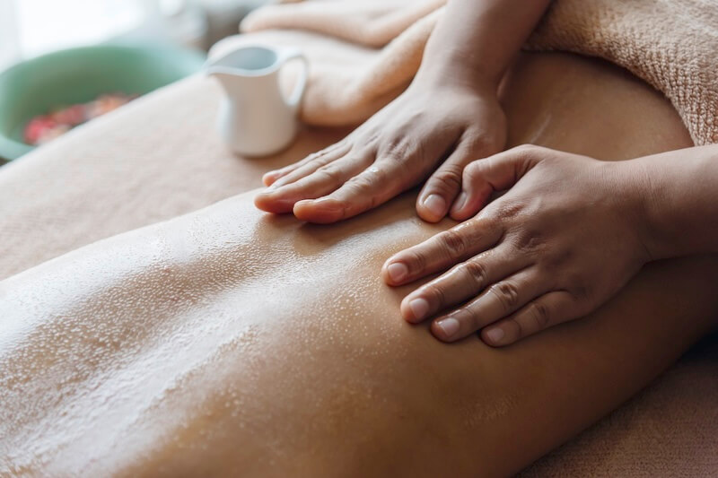 Das Bild zeigt eine Frau mit Massageöl auf dem Rücken, die gerade von einer Masseurin eine Aroma Teilkörpermassage im Hotel Warnemünder Hof erhält.