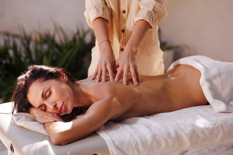 Das Bild zeigt eine Frau auf einem Massagetisch, die im Spa Hotel Warnemünder Hof eine klassische Teilkörpermassage geießt.