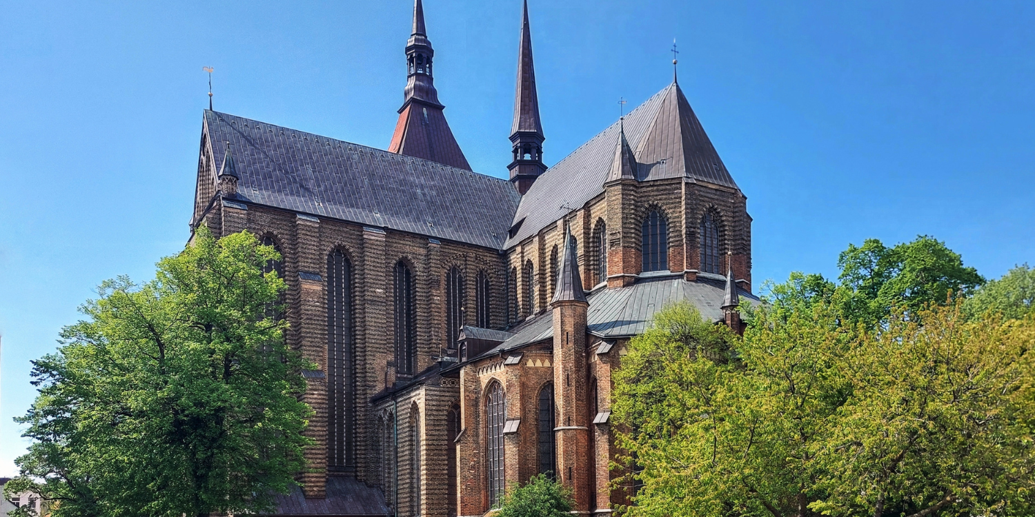 St. Marien Kirche Rostock umgeben von blauem Himmel und Bäumen