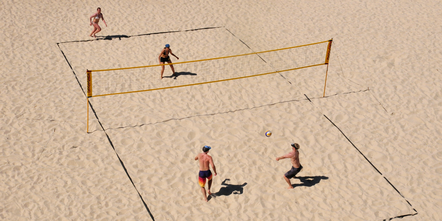 Beachvolleyball-Feld am Strand mit vier spielenden Personen