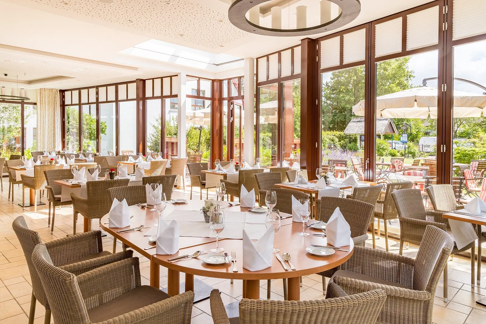 Das Bild zeigt die helle und freundliche Veranda mit vielen gedeckten Tischen im Hotelrestaurant "Uns Hüsung".